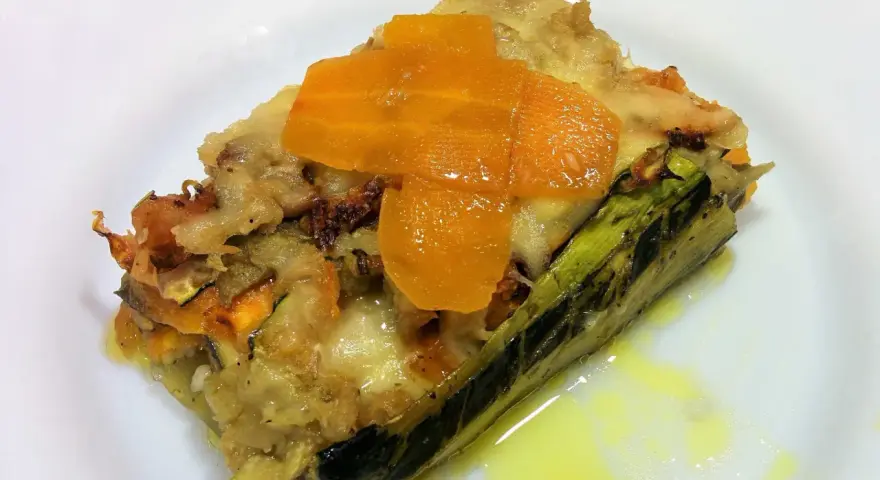 Deliciosa lasaña de verduras sin pasta, con capas de calabacín, zanahoria y queso fundido, servida en un plato blanco.