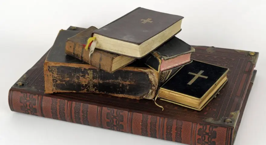 Stapel alter Bücher, einige mit Kreuzen auf dem Einband.