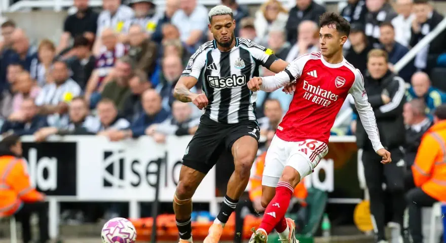 Piłkarze Newcastle i Arsenal walczą o piłkę na boisku. Intensywna akcja podczas meczu.