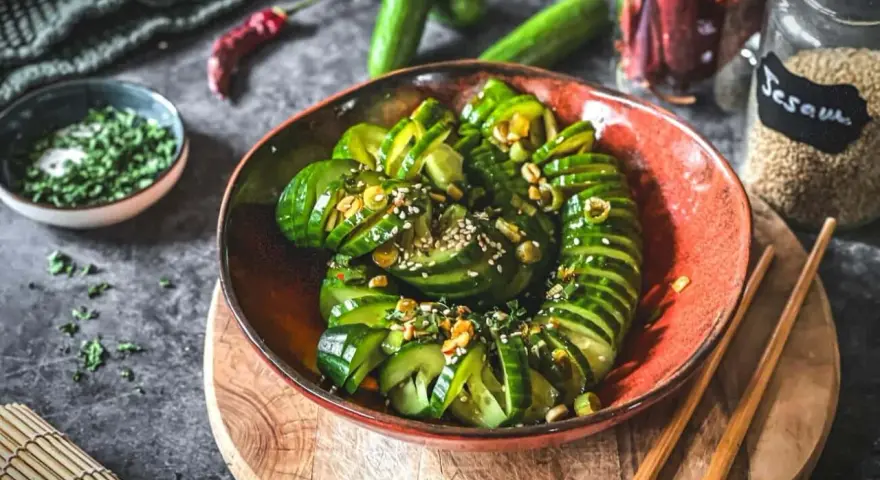 Ein erfrischender asiatischer Gurkensalat, garniert mit Sesam und Kräutern, bereit zum Genießen.