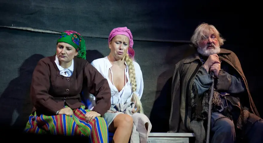 Trzech aktorów w strojach ludowych na scenie Teatru Muzycznego Gdynia.