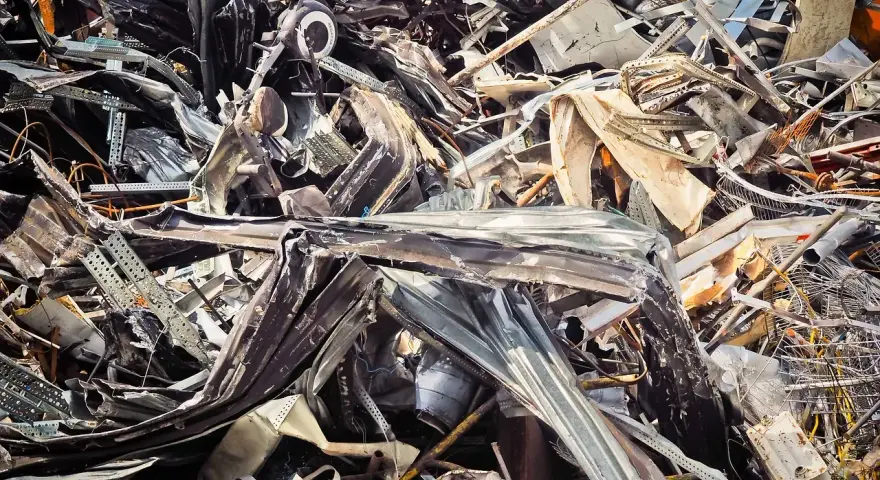 Góra złomu, poskręcane metalowe elementy, tworzące chaotyczną strukturę. Widoczne fragmenty blachy, prętów i innych odpadów. Kod odpadu: 17 04 05.