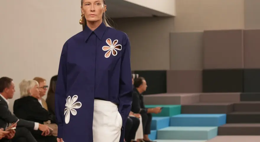 Modella con camicia blu Fendi e pantaloni bianchi, un'icona di stile che racconta la sua storia.