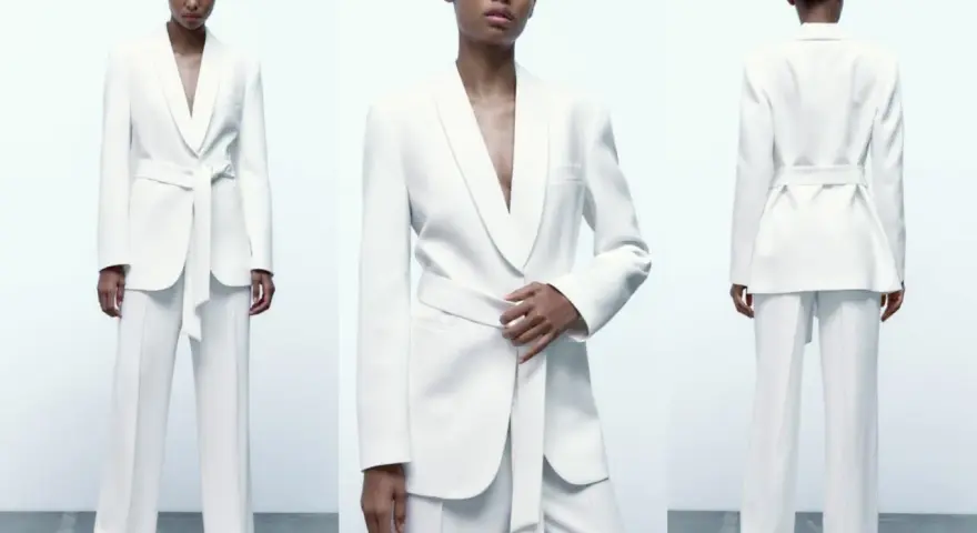 Mujer posa con un elegante traje blanco de pantalón y blazer con cinturón. Un look sofisticado para combinar traje blanco mujer.