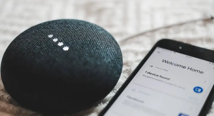 A smart speaker and phone display "Welcome Home" and "1 device found," showcasing modern iot design for a connected home.