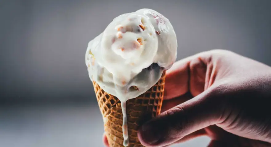 Eine Hand hält ein schmelzendes Rhabarber-Eis in einer Waffel.