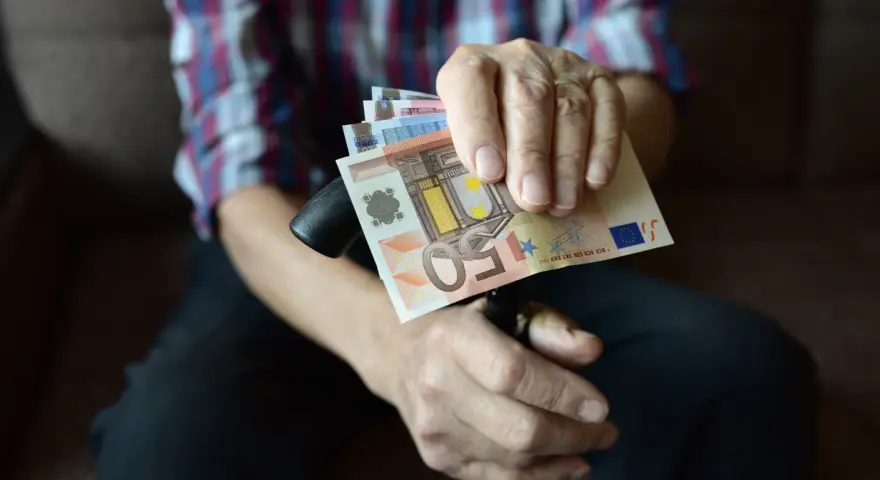 Dłoń trzyma banknoty euro, które są walutą Słowenii.