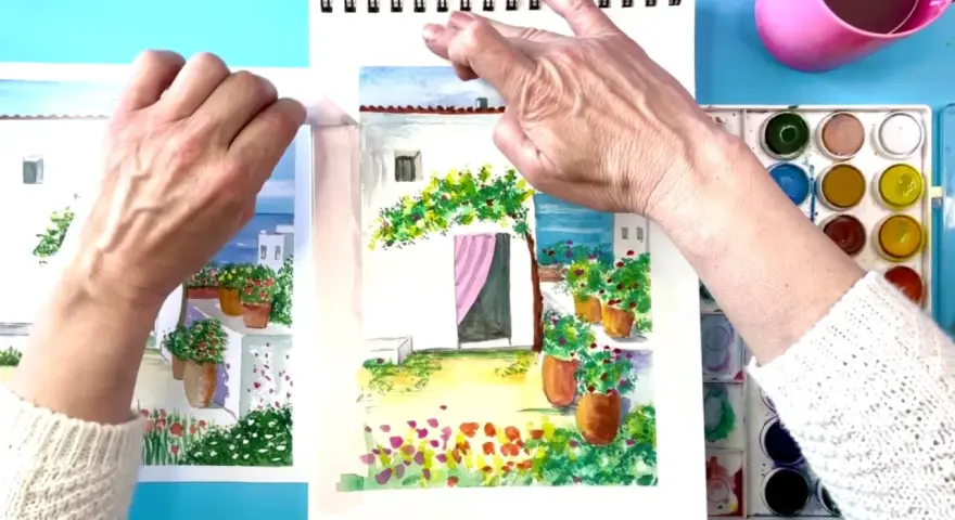 Manos pintando acuarelas fáciles de hacer: un patio con flores y una casa blanca.