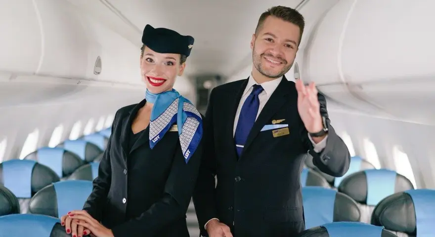 Uśmiechnięta stewardessa i steward w uniformach LOT-u, gotowi do lotu. Marzysz, jak zostać stewardessą? To początek Twojej przygody!