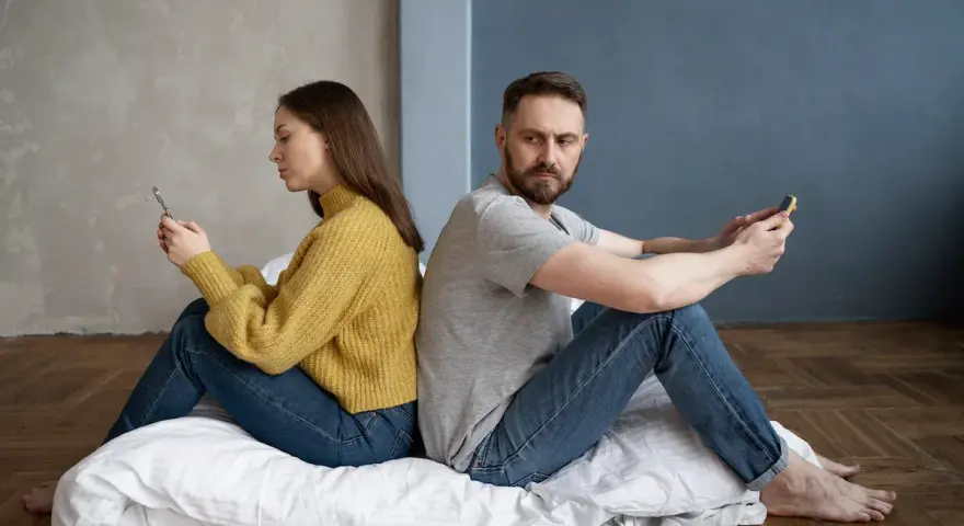 Para siedzi plecami do siebie, wpatrzona w telefony. Czy to przykład breadcrumbing co to znaczy?