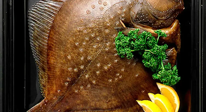 Hel, helgrillad piggvar i ugn, garnerad med persilja och citronklyftor.