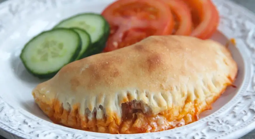 En gyllene pirog med ost och tomatsås, serverad med gurka och tomat. Ett perfekt piroger recept för en snabb måltid.