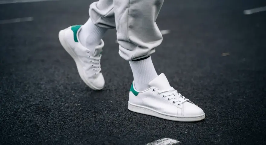 Un paio di sneakers bianche con dettagli verdi, simbolo di stile e comfort. Il loro significato va oltre la moda, rappresentando libertà di movimento.