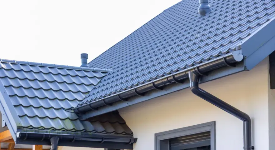 Szary dach z dachówki ceramicznej, rynny i komin. Sprawdź, jaka jest dachówka ceramiczna cena za m2.