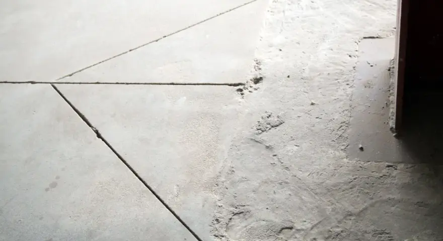 Szara podłoga z widoczną dylatacją i nierównościami.