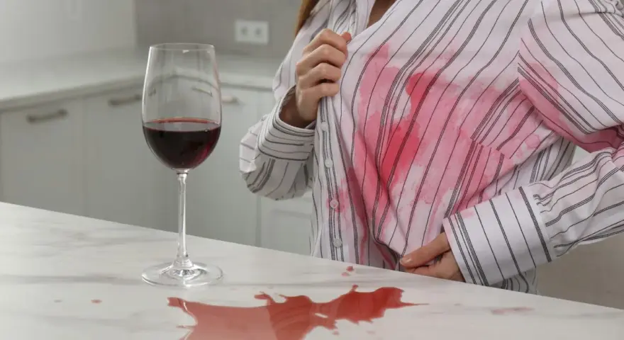 Kieliszek wina przewrócony na blacie, rozlana plama na białej koszuli. Jak usunąć plamę z wina?
