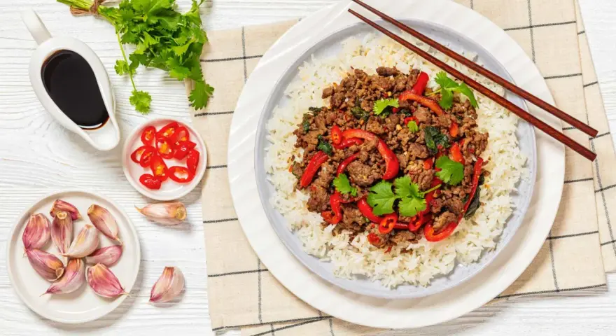 Delicioso arroz con carne picada, pimientos rojos y cilantro fresco. Acompañado de salsa de soja, chiles y ajos.