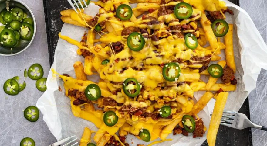 Pommes Frites mit Hackfleisch, Bohnen, Mais und geschmolzenem Käse, garniert mit Jalapeños. Ein köstliches Gericht mit **Chilli Cheese Sauce**.