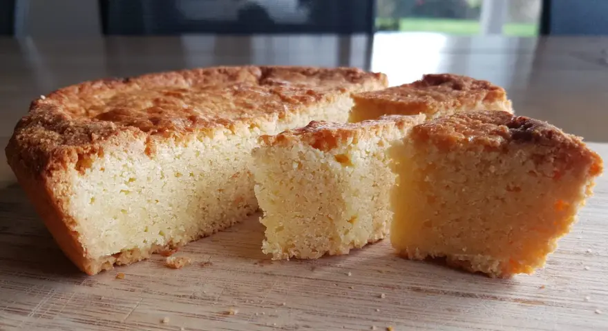 Un delicioso pastel bretón, dorado y esponjoso, cortado en porciones sobre una tabla de madera.