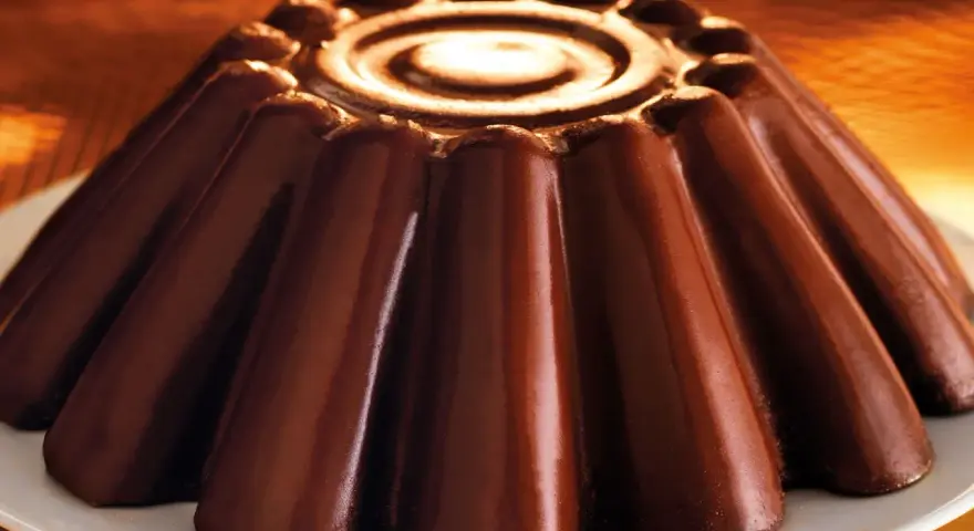 Budino al cioccolato lucido e invitante, con un disegno a spirale al centro e un bordo decorato.