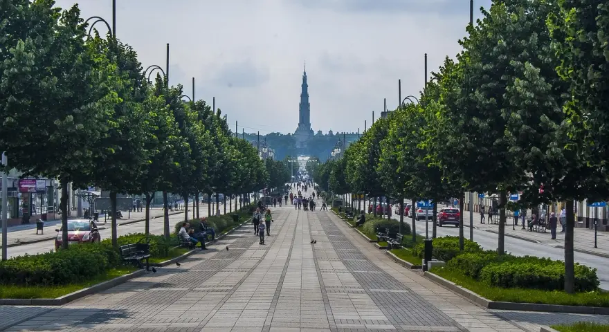Aleja z drzewami i bazyliką w tle. Spacer po alei to jedne z częstochowskich atrakcji dla dzieci, które mogą podziwiać architekturę i poczuć atmosferę miasta.