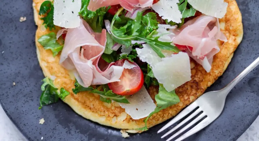 Pyszny przepis na omlet na słono z szynką parmeńską, parmezanem, pomidorkami i rukolą. Idealny na szybki obiad lub kolację.