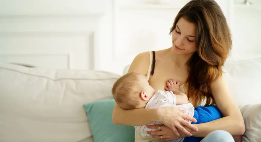 Ciepła chwila karmienia piersią. Mama z miłością patrzy na swoje dziecko, wspierając naturalną laktację.