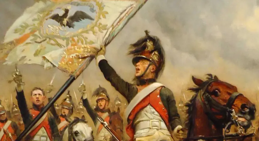 Un porte-étendard, au cœur des 10 batailles de Napoléon, brandit fièrement l'aigle impérial. Cavaliers et chevaux chargent.