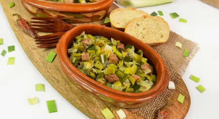 Zwei Terrinen mit Lauchgemüse und Fleischstücken, serviert mit Brot. Ein leckeres Beispiel für Lauch Rezepte.