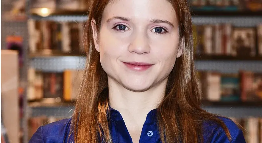 Eliza Rycembel, uśmiechnięta, w niebieskiej bluzce, na tle regałów z książkami. Jej życie prywatne jest tematem zainteresowania.