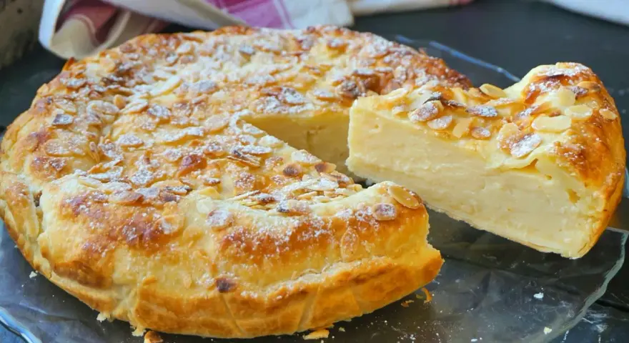 Tarta de hojaldre y crema pastelera, cubierta de almendras laminadas y espolvoreada con azúcar glas. ¡Un postre irresistible!