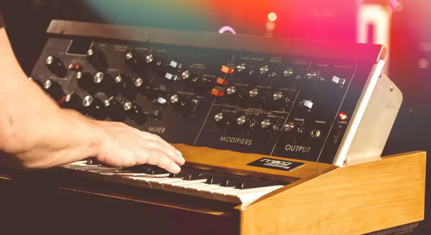 Hand spielt auf einem legendären Minimoog-Synthesizer, der den unverwechselbaren Sound der 70er Jahre prägte.