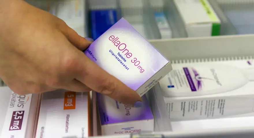 Hand greift nach ellaOne 30mg Tablette. Informationen zu ellaOne Nebenwirkungen sind auf der Packung zu finden.