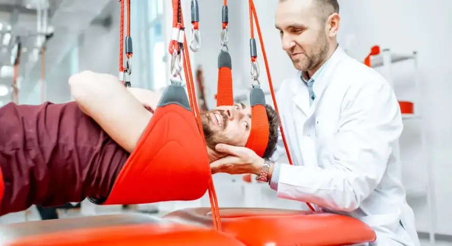 Fizjoterapeuta pomaga pacjentowi podczas terapii wiszącej. Często rehabilitacja kręgosłupa jest kluczowa dla powrotu do zdrowia.