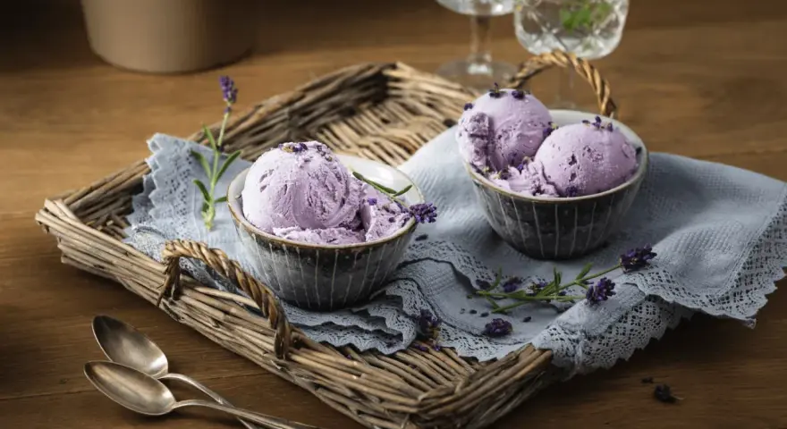 Zwei Schalen mit cremigem Lavendeleis, garniert mit Lavendelblüten. Ein köstliches Lavendeleis Rezept zum Nachmachen.
