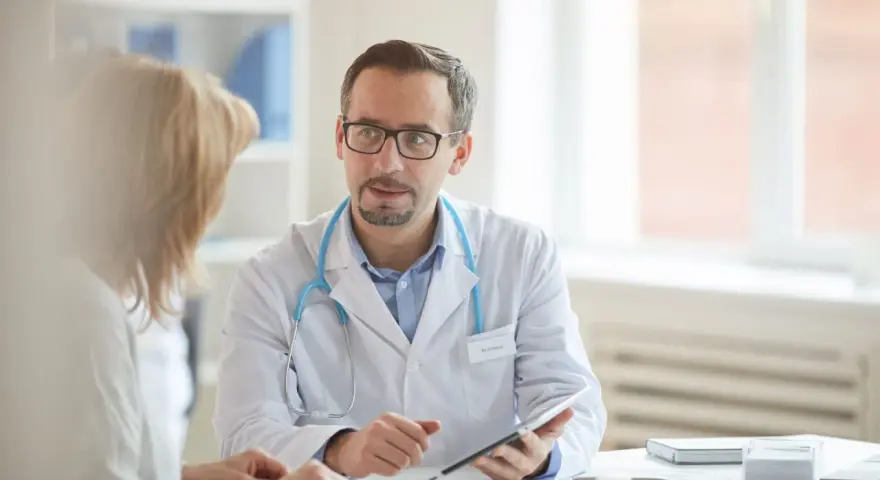 Arzt erklärt Patientin Ergebnisse, vielleicht den lipase wert, auf einem Tablet.