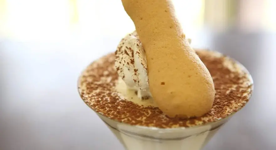 Pyszne tiramisu w kieliszku, posypane kakao, z biszkoptem. Idealne, gdy szukasz, czym zastąpić amaretto.