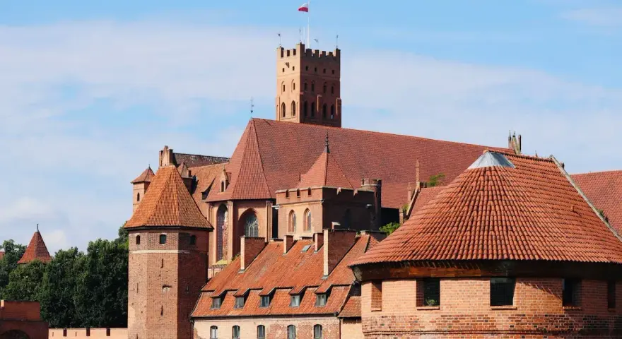 Zamek w Malborku, wpisany na listę **UNESCO Polska**, to imponująca twierdza z czerwonej cegły z charakterystycznymi wieżami i dachami.
