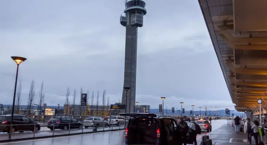 Wieża kontrolna na oslo lotnisko. Ludzie z bagażami wsiadają do vana.