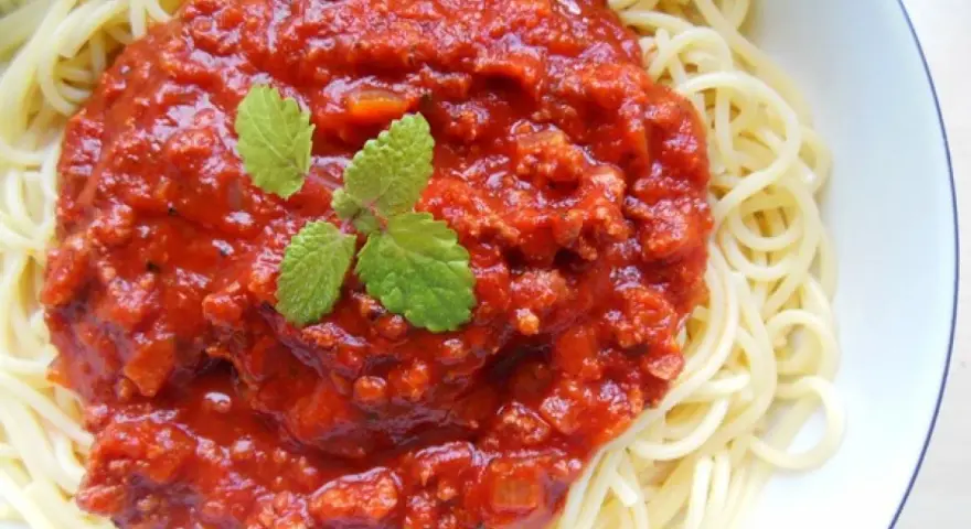 Spaghetti z bogatym sosem bolońskim i listkami mięty.