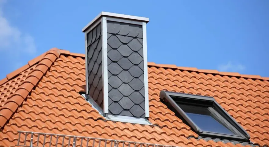 Schornstein verkleiden innen mit Schieferplatten. Dachziegel und Dachfenster sind zu sehen.