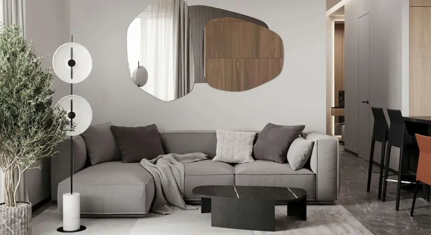 Nowoczesny salon z szarą sofą, geometrycznym lustrem i designerską lampą.