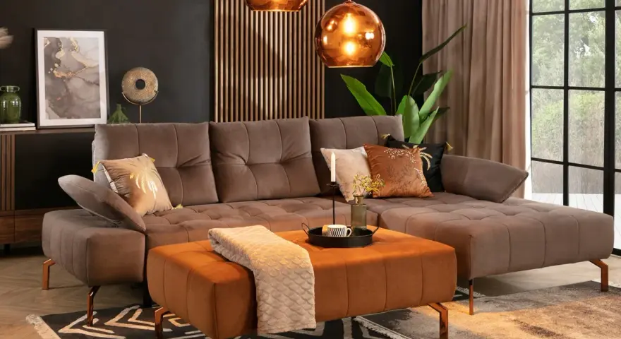 Elegancki salon z sofą w kolorze taupe, który jest pięknym odcieniem brązu z szarym akcentem. Wygodny narożnik i pufa tworzą przytulną przestrzeń.