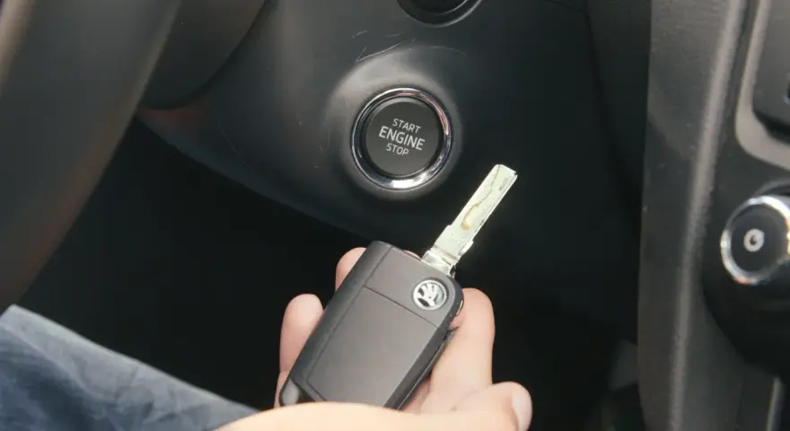 Słaba bateria w kluczyku może utrudnić odpalanie auta. Kluczyk z logo Skody leży w dłoni obok przycisku Start/Stop.