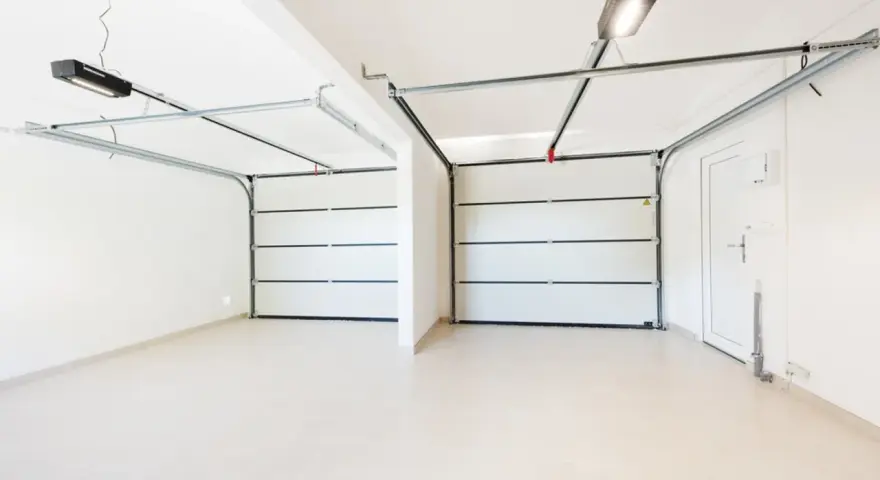 Dos puertas de garaje se abren a un espacio limpio y moderno, listo para pintar el garaje original.