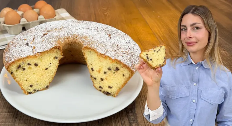 Un soffice ciambellone al bicchiere con gocce di cioccolato, spolverato di zucchero a velo, pronto per essere gustato.