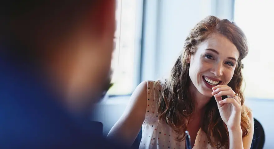Giovane donna con capelli rossi sorride, pensando al suo futuro dopo la psicologia laurea magistrale.