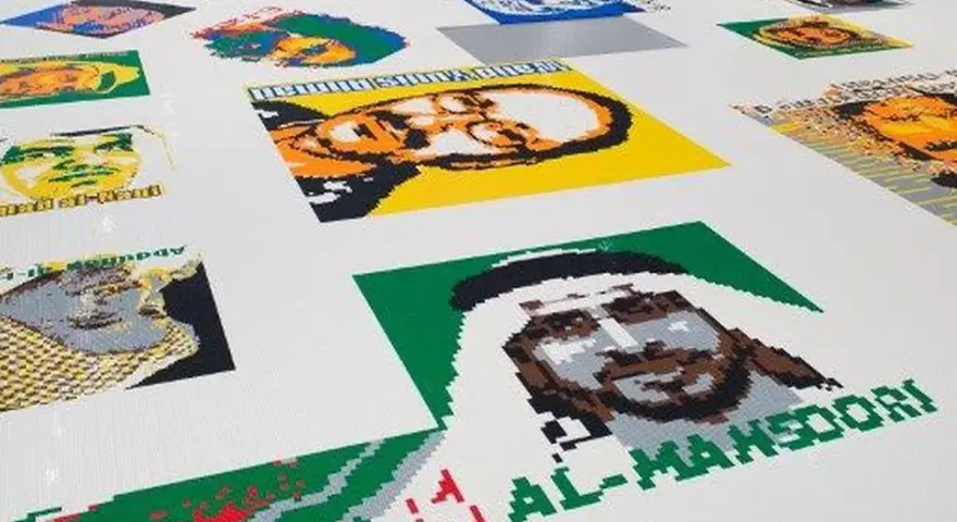 Portraits de personnalités réalisés en briques Lego, dans le style d'Ai Weiwei. L'œuvre est étendue sur un sol blanc.