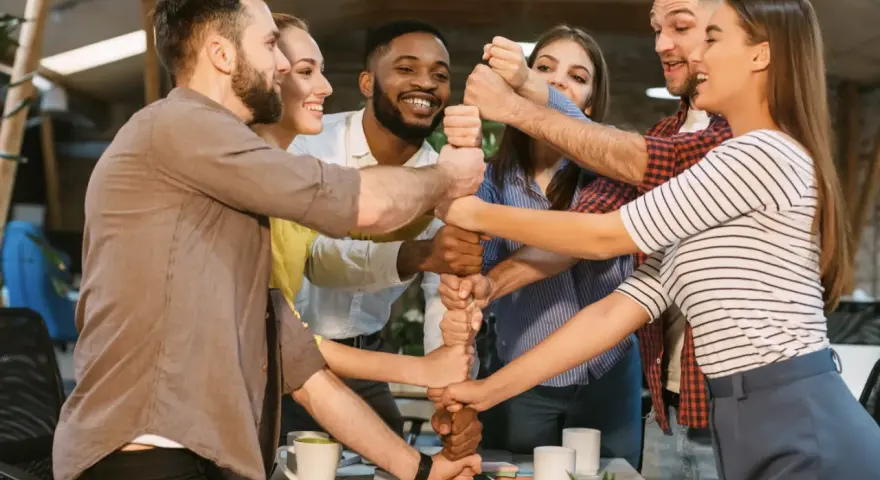 Une équipe soudée célèbre un événement team building, unissant leurs poings pour symboliser la force collective et la réussite.