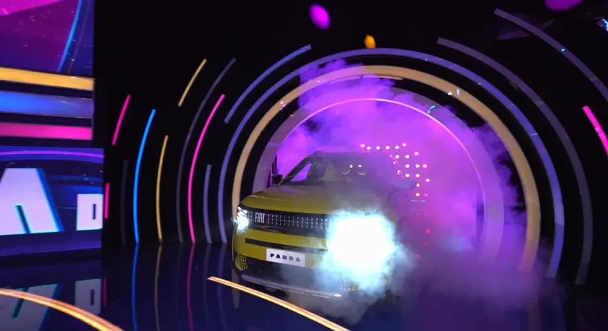 Żółty Fiat Panda wyjeżdża z dymu i świateł w kole fortuny.